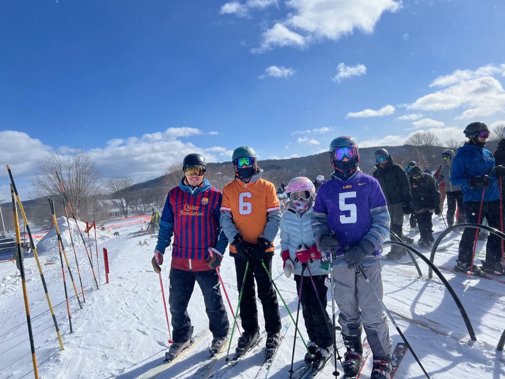Skiers wearing sports jerseys at the base of the mountain.